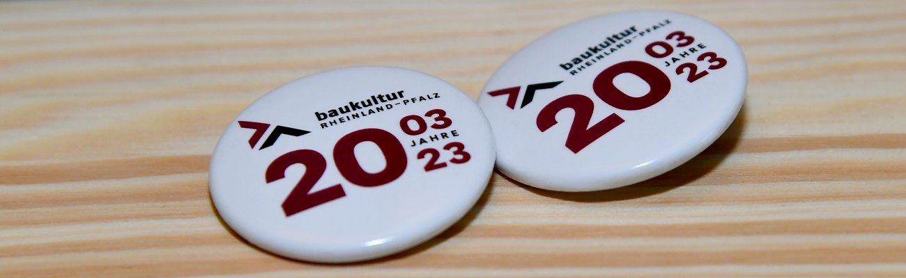 Zwei Buttons mit der Aufschrift Baukultur Rheinland-Pfalz, 20 Jahre, 03.23