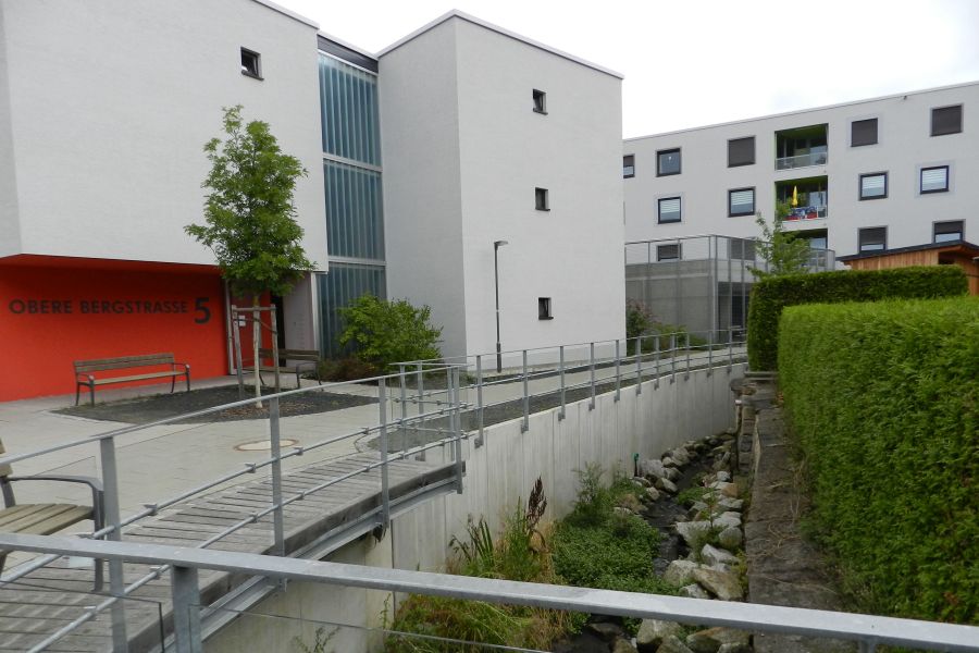 Blick auf die Fassade mit Bachlauf im Vordergrund