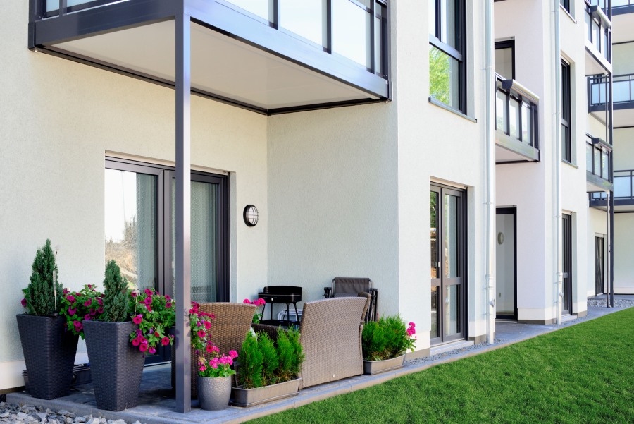 Blick entlang der Fassade, im Vordergrund möblierte Terrasse